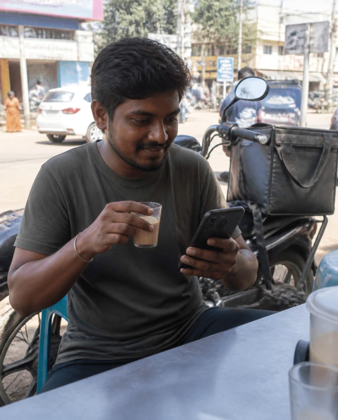 Delivery rider on a tea break watching a Tamil video on his smartphone