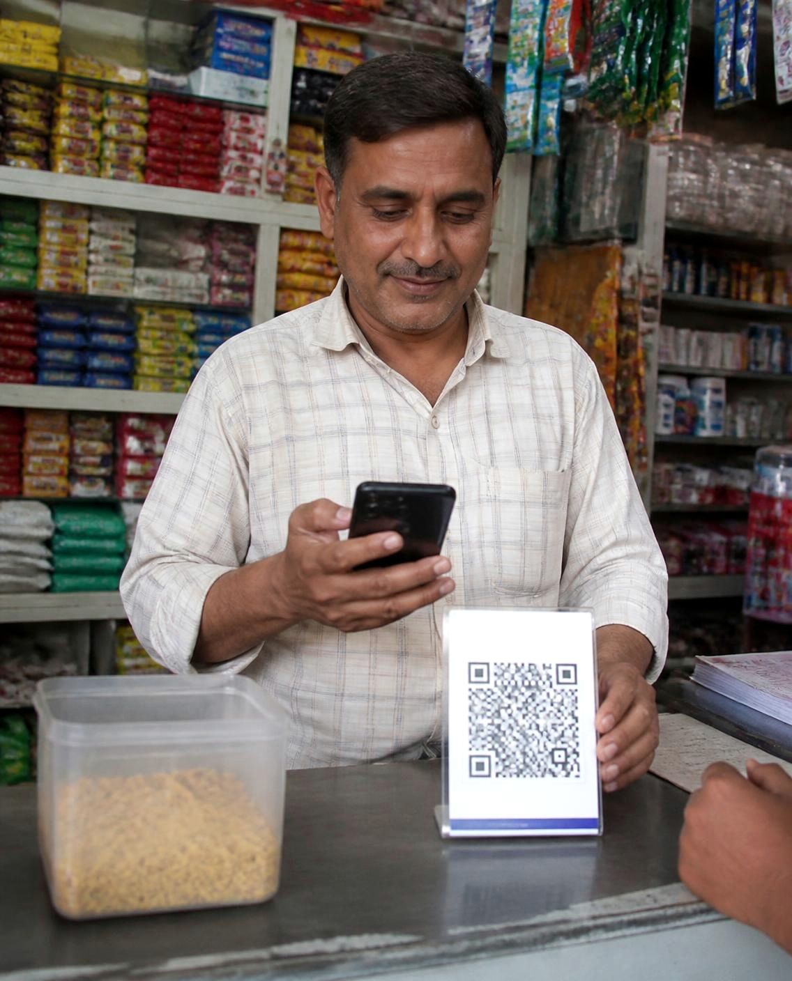Shopkeeper taking a UPI payment at the counter of his neighbourhood store